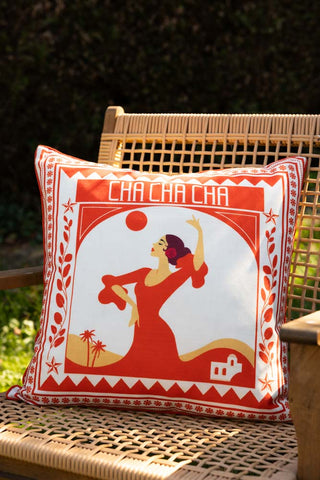 The Red Cha Cha Cha Outdoor Cushion styled outdoors on a woven chair.