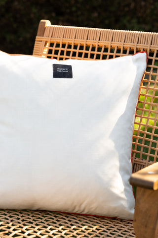 The reverse side of the Red Cha Cha Cha Outdoor Cushion, displayed outdoors on a woven chair.