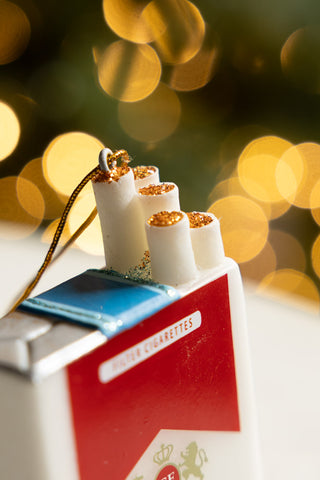 Close-up of the Red Cigarette Pack Christmas Tree Decoration with fairy lights in the background.