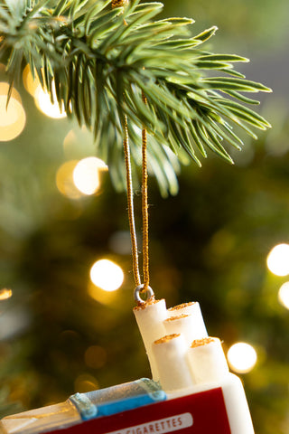 Close-up of the hanging loop of the Red Cigarette Pack Christmas Tree Decoration, hanging from A Christmas tree branch.