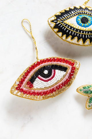 The Red Eye Beaded Hanging Christmas Tree Decoration on a white surface with other decorations.