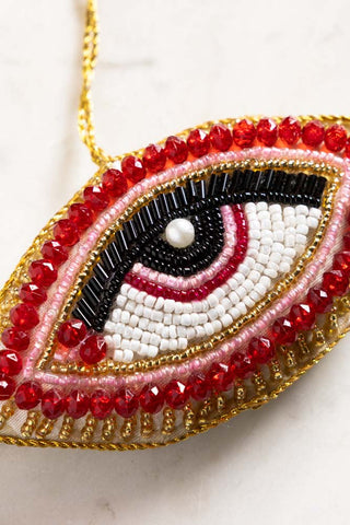 Close-up of the Red Eye Beaded Hanging Christmas Tree Decoration on a white surface.