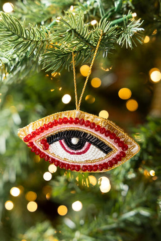 The Red Eye Beaded Hanging Christmas Tree Decoration hanging from the branch of a Christmas tree.