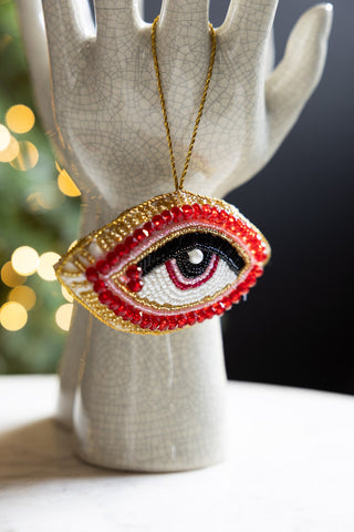 The Red Eye Beaded Hanging Christmas Tree Decoration hanging from a ceramic scultpure.
