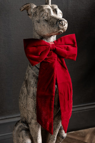 The Red Velvet Bow Christmas Decoration styled on a dog statue.