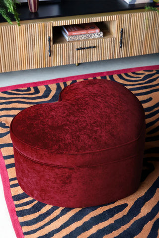 The Red Heart Storage Footstool on a rug in a living room.