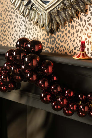 The Red Antique-Effect Bauble Christmas Garland styled on a fireplace.