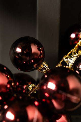 Close-up of the baubles on the Red Antique-Effect Bauble Christmas Garland in front of a dark background.