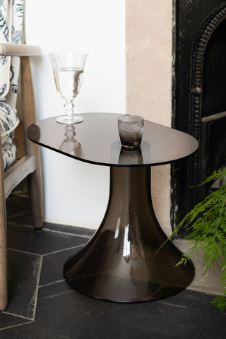The Retro Asymmetric Side Table in Espresso styled with some drinking glasses on, next to a chair and plant.