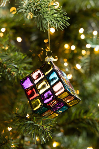 The Retro Colourful Cube Christmas Tree Decoration styled hanging from the branch of a Christmas tree with fairy lights.