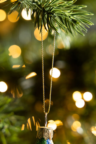 Close-up of the hanging loop of the Retro Troll-Inspired Christmas Tree Decoration, hanging from the branch of a Christmas tree.