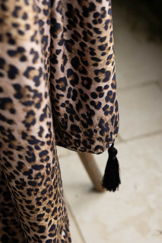 A close up of the Signature Leopard Print Velvet Throw with Tassels, showing the leopard print and black tassels. 
