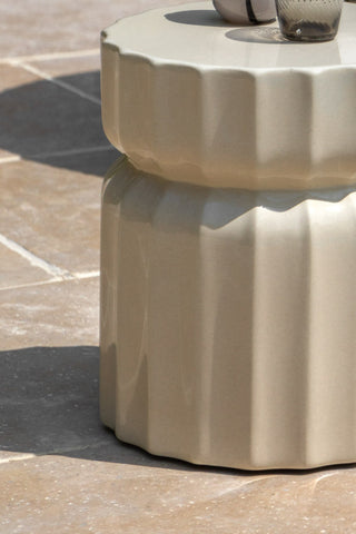 Close-up of the Ribbed Edge Round Side Table in Ivory Glaze styled outdoors with some glasses on.