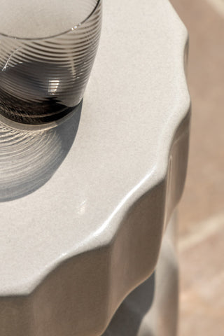 Close-up of the top of the Ribbed Edge Round Side Table in Ivory Glaze with a glass tumbler on.
