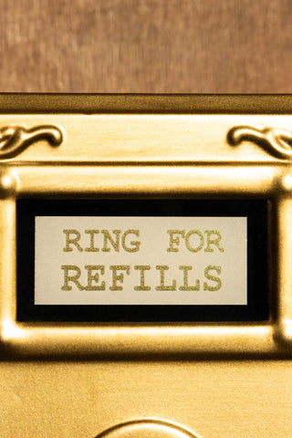 The text on the Ring For Refills Gold Wall Ornament. 