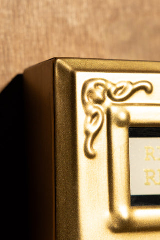 The ornate detailing of the Ring For Refills Gold Wall Ornament. 