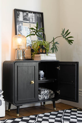 The Black & Gold Ringo Small Sideboard with one door open, styled with various accessories on/around it.