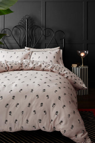 The Rock & Rose Duvet Cover and Pillow Case Set styled on a black bed, with a rug, bedside table, lamp and books.