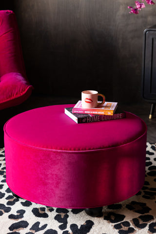 The Round Footstool in Harry's Hot Pink Velvet styled with some books and a mug on.
