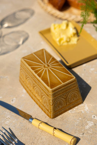 The Rustic Mustard Yellow Butter Dish with the lid off, styled on an outdoor table.