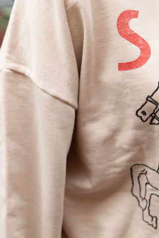 Close-up of the sleeve of the Saddle Up Cowboy Sweatshirt in Oat.