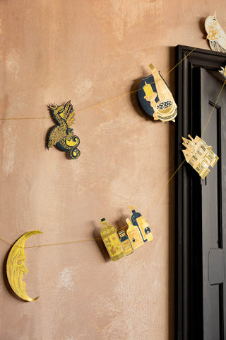 The Samhain Sewn Paper Halloween Garland shown on a plaster wall. 