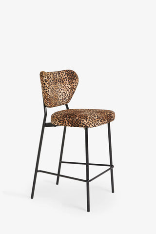 The Leopard Print Velvet Bar Stool seen from an angle on a white background.