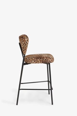 The Leopard Print Velvet Bar Stool seen from the side, on a white background.