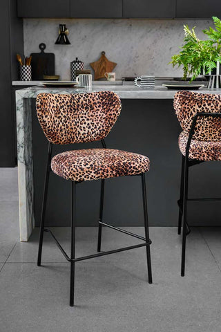 Two Leopard Print Velvet Bar Stools in front of a kitchen island.