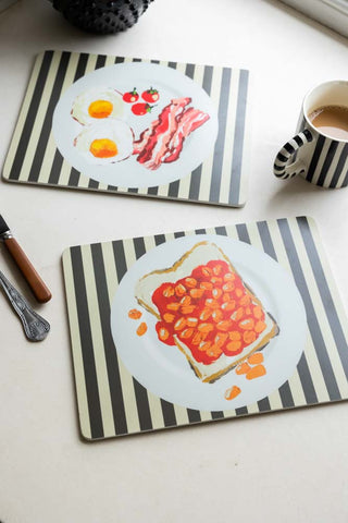 Set Of 2 Breakfast Placemats displayed on a table with a mug, cutlery and jug.