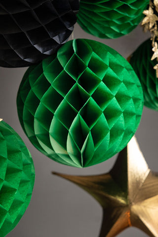 Green honeycomb balls hanging from a table stand.