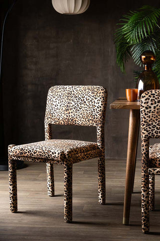 The Set Of 2 Signature Leopard Velvet Dining Chairs styled next to a table.