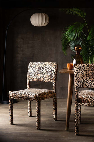 The Set Of 2 Signature Leopard Velvet Dining Chairs with a floor lamp, dining table, plant and some accessories.