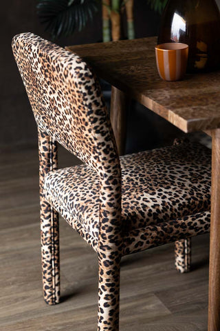 The reverse side of one of the Set Of 2 Signature Leopard Velvet Dining Chairs, styled at a dining table.