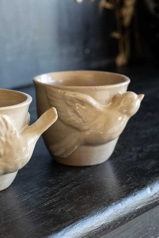 Lifestyle image of the Set Of 2 Taupe Bird Mugs showing the detail of one design