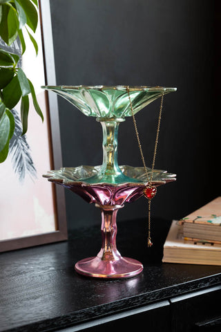 The Set Of 2 Vintage-Style Coloured Glass Display Dishes stacked together and styled on a sideboard with some other accessories.