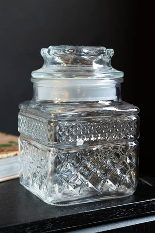 One of the Set Of 2 Vintage-Style Glass Storage Jars displayed on a wooden surface.
