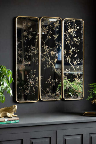 The Set of 3 Framed Rectangular Chinoiserie Decorative Mirrors shown on the wall in a black room above a sideboard. 