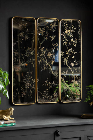 The Set of 3 Framed Rectangular Chinoiserie Decorative Mirrors shown at an angle against a black wall. 