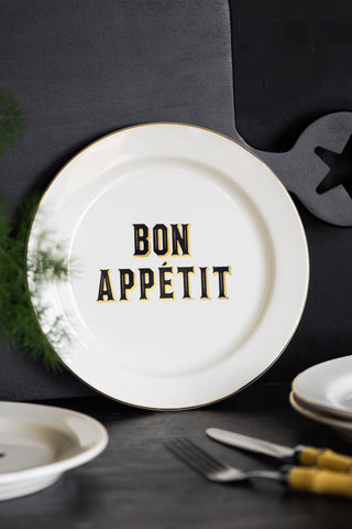 The Set Of 4 Bon Appetit White Bistro Side Plates displayed on a black sideboard with other kitchen accessories.