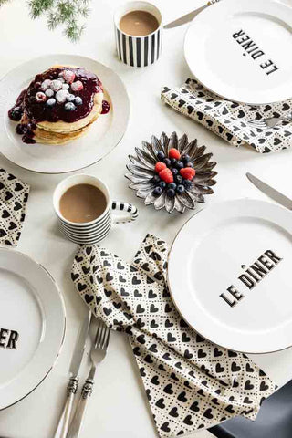 Table spread of le Diner Plates, stipey mugs filled with coffee and heart napkins.