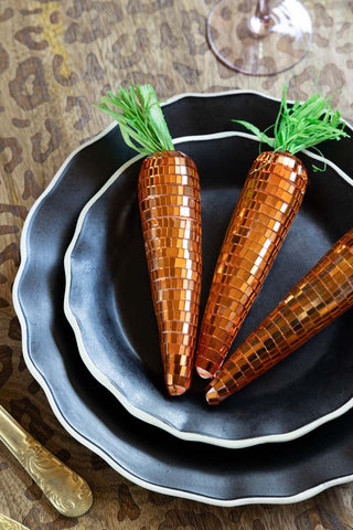 Three of the Set Of 6 Disco Carrot Easter Decorations styled on plates on a dining table.