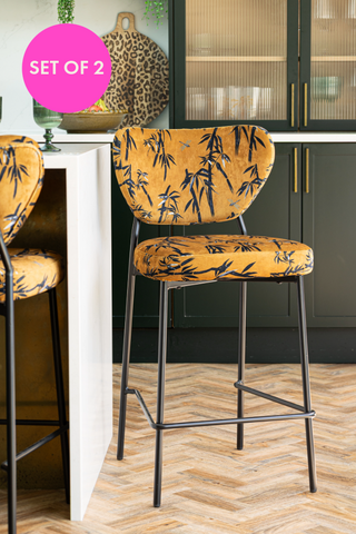 The Set of 2 Bar Stools in Bamboo Velvet styled at a breakfast bar, with an icon that says 'set of 2' in a pink circle.