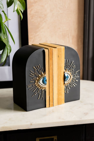 The Set of 2 Black Mystic Eye Bookends shown on a marble sideboard against plaster walls. 