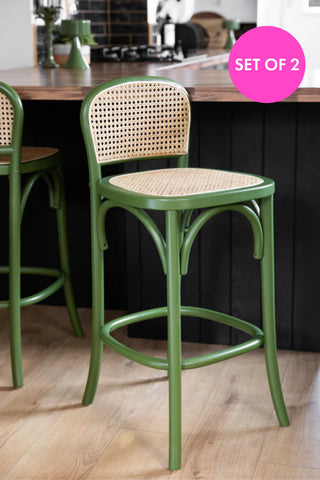 Two of the Chez Pitou Wood & Woven Cane Bar Stool in Green styled ina  kitchen next to a breakfast bar.