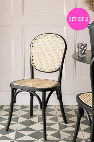 Parisian-inspired cane and black wood chair placed beside a round dining table.