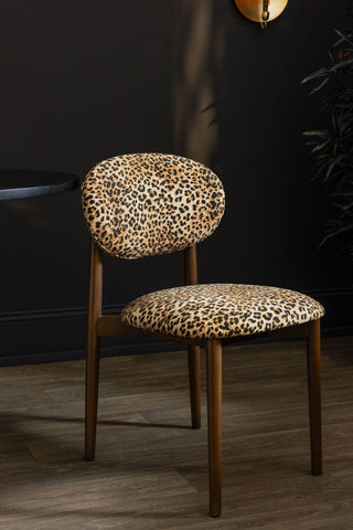 One of the Set of 2 Leopard Wooden Dining Chairs, styled on a wooden floor next to a table and a plant.