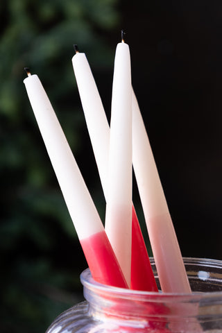 The Set Of 2 Pink Dinner Candles styled with the matching red versions and displayed together in a clear glass jar.