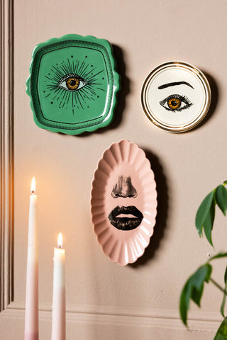 The Set of 3 Colourful Face Wall Plates displayed on a neutral wall above some lit candles and a plant.