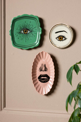 The Set of 3 Colourful Face Wall Plates displayed on a neutral wall above a plant.